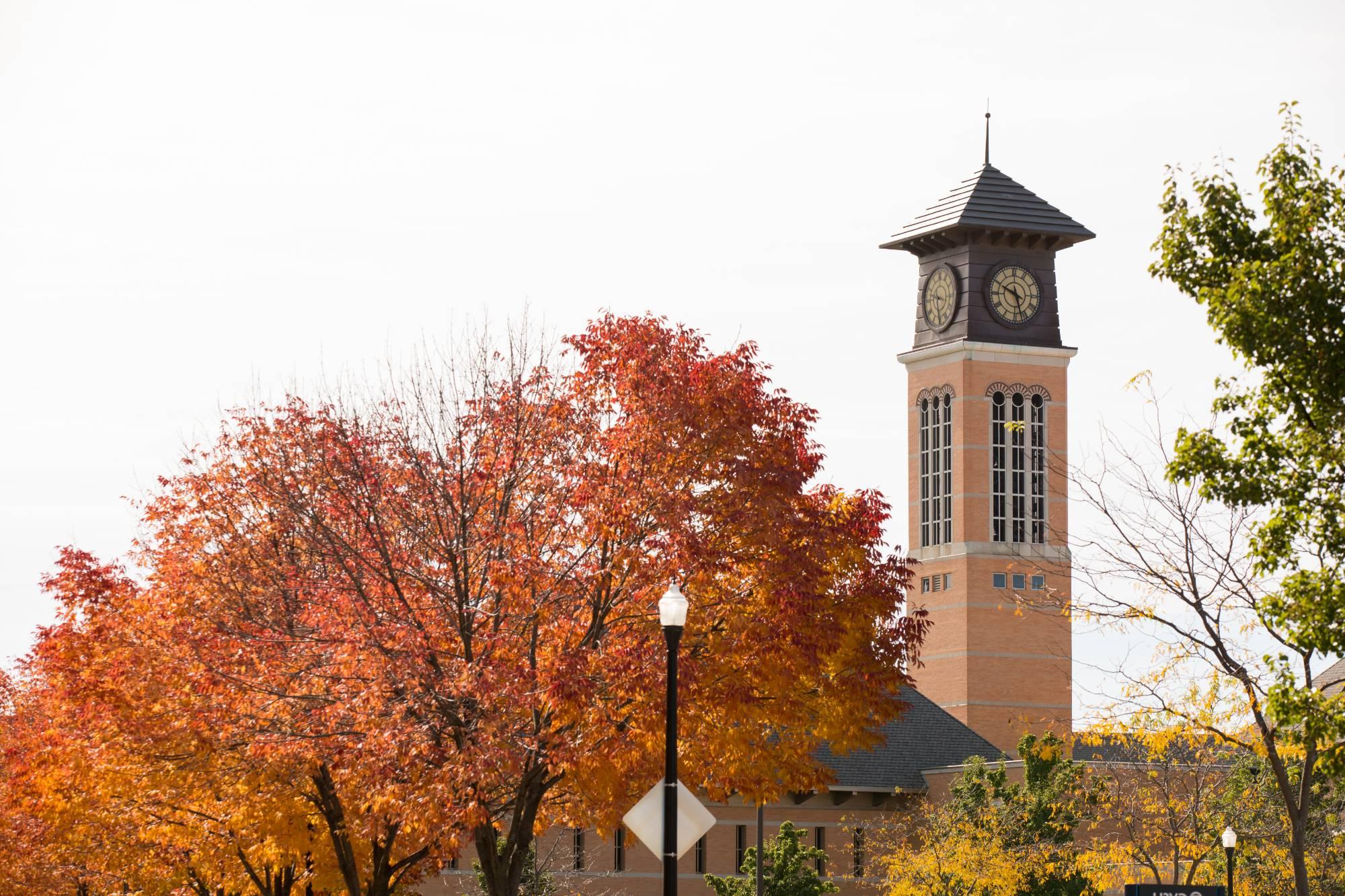 orange and yellow trees with clocktower and blue skies in the background